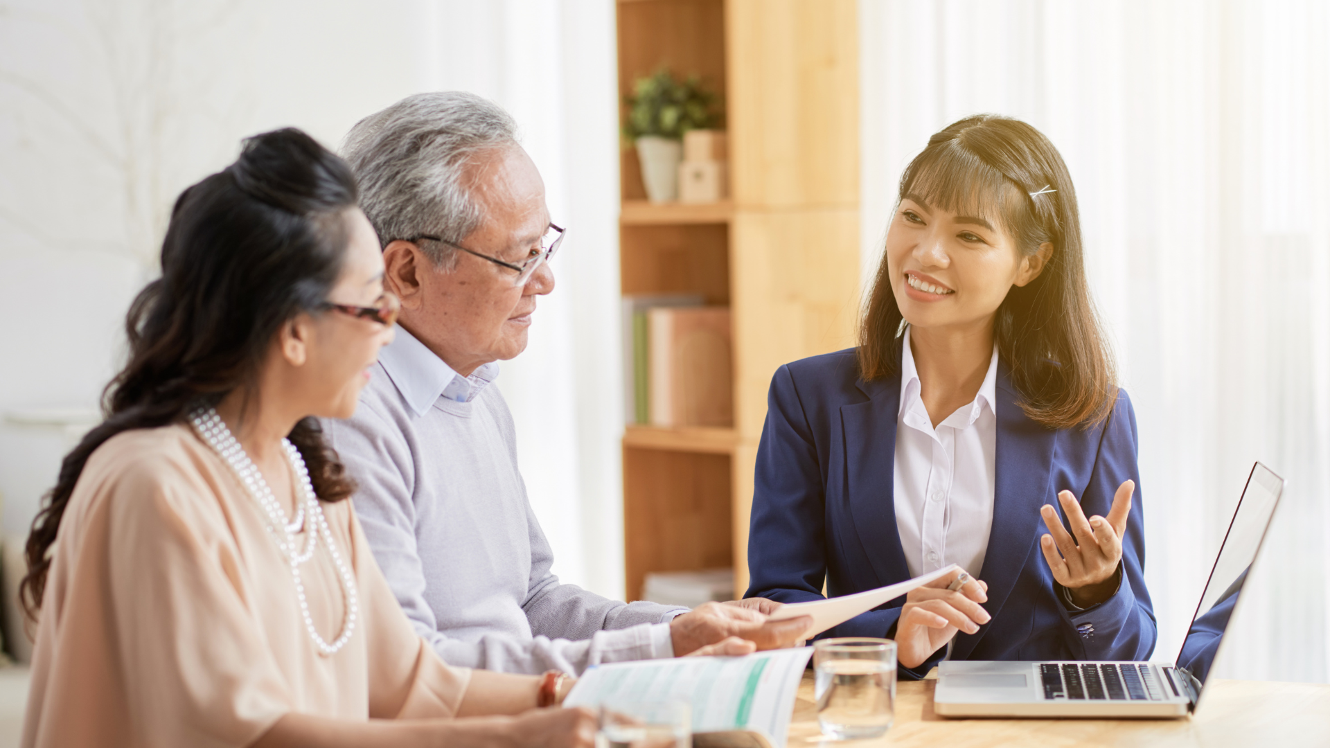 professional woman helping elderly couple with insurance paperwork